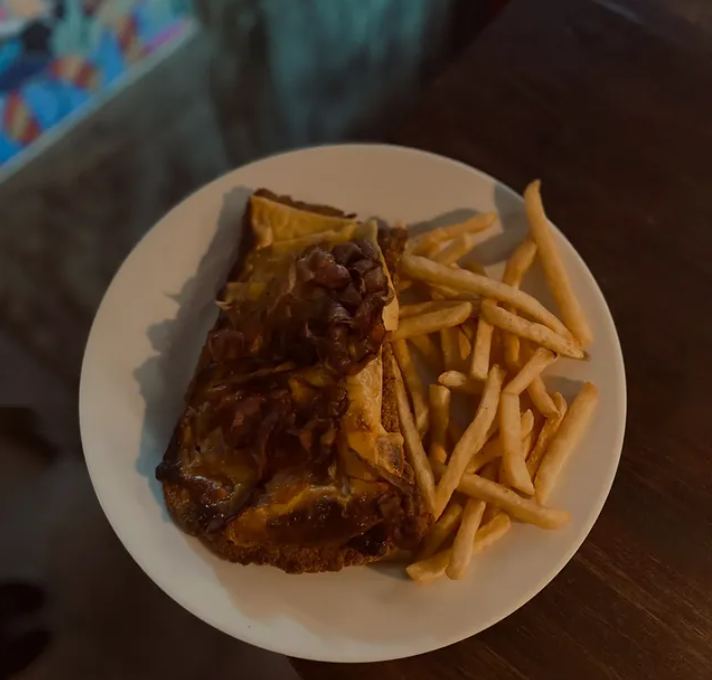 Plato gratinado con papas fritas sobre mesa de madera