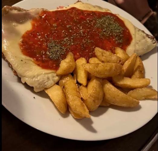 Milanesa napolitana con salsa de tomate, queso gratinado y papas rústicas